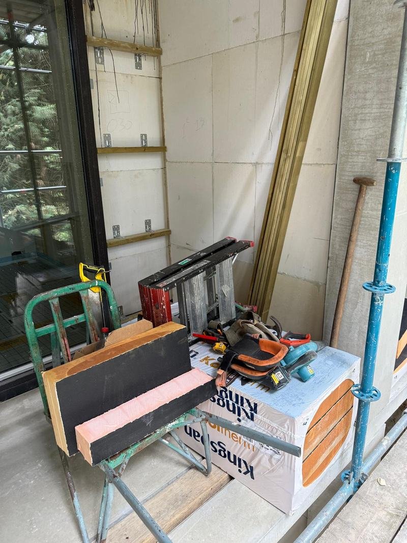 Bouwplaats op een steiger met isolatieplaten, regelwerk op de muur en gereedschap